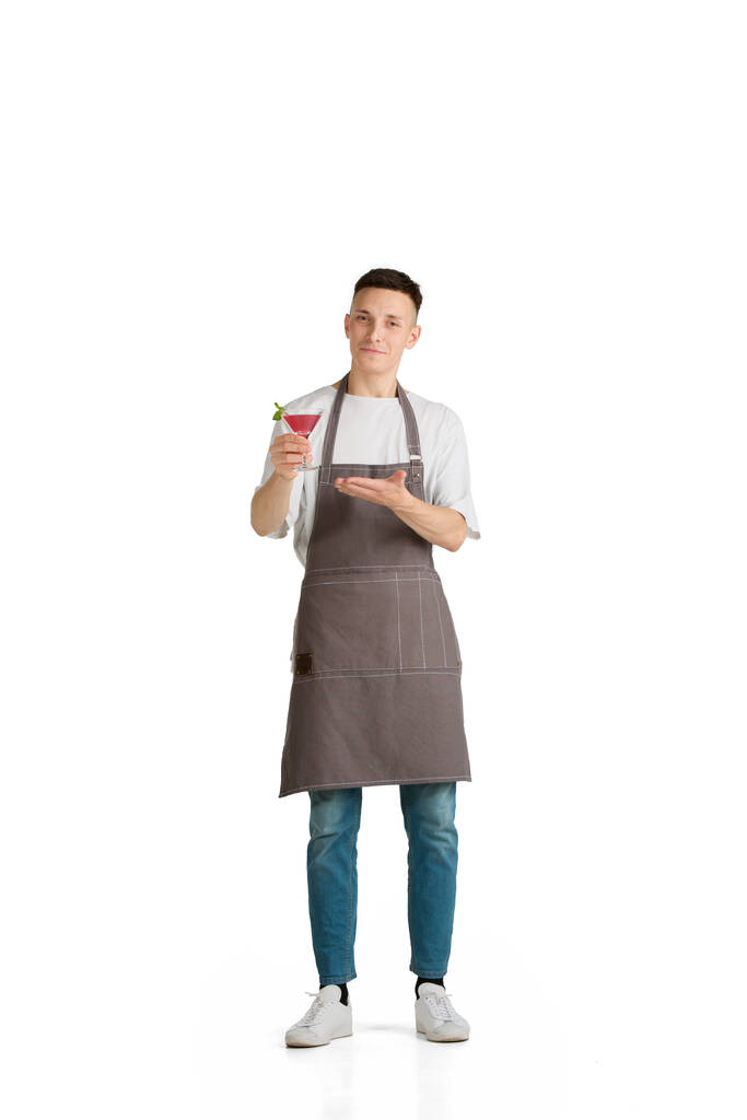 Retrato aislado de un joven camarero caucásico o camarero en delantal marrón sonriendo - Foto, imagen