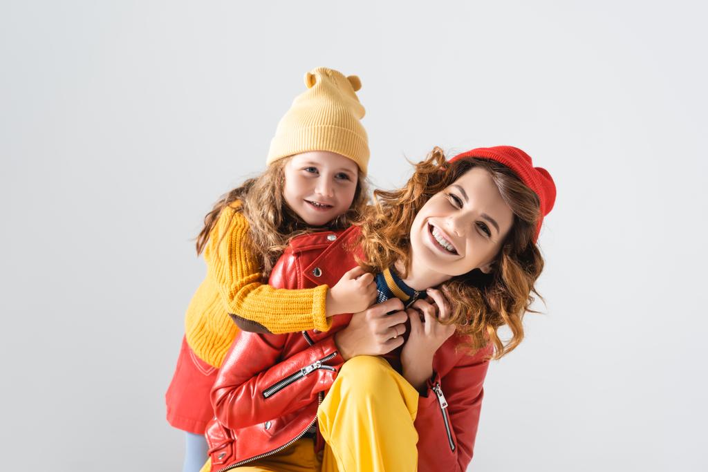 mother and daughter in colorful red and yellow outfits hugging isolated on grey - Photo, Image