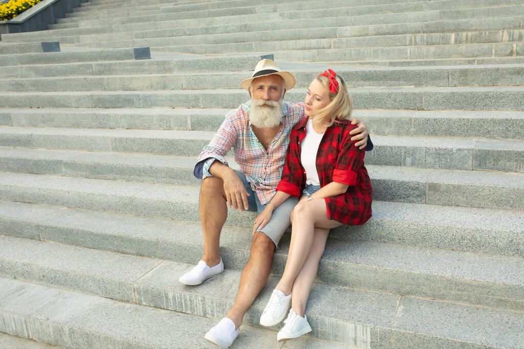 Couple touristique romantique assis sur les escaliers. Homme âgé barbu et jeune femme. - Photo, image