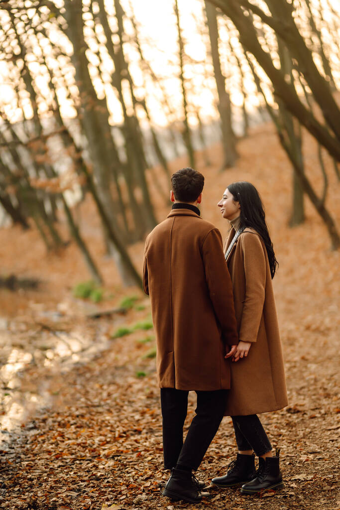 Schönes Paar, das zusammen Spaß im herbstlichen Wald hat. Modepaar genießt Herbstwetter. Mode, Lifestyle und Herbststimmung. - Foto, Bild