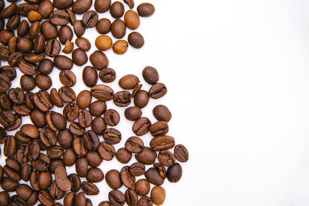 Kávová zrna jsou roztroušena na bílém pozadí. Textura kávy.. - Fotografie, Obrázek