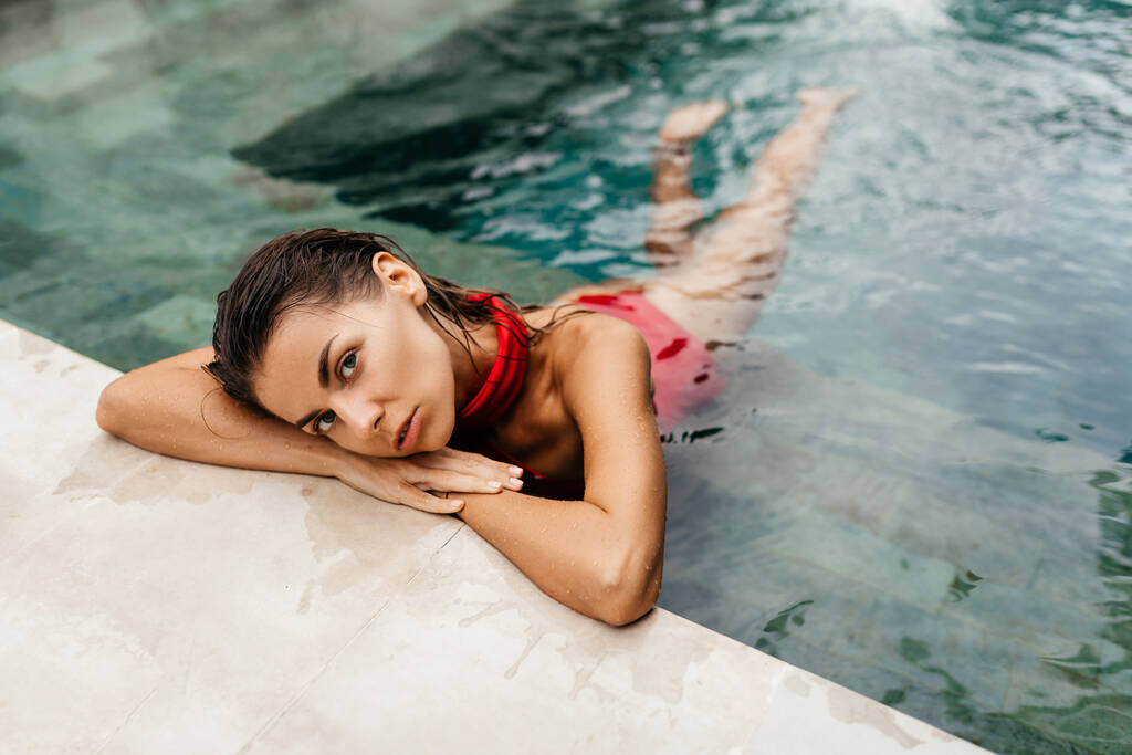 mujer en traje de baño rojo relajante en la piscina - Foto, Imagen