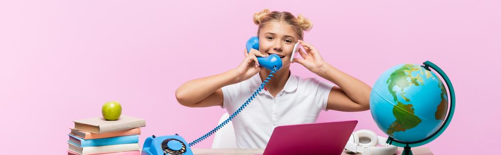 Panoraama laukaus koulutyttö puhuu puhelimessa ja älypuhelin lähellä kannettavaa tietokonetta ja maailmaa eristetty vaaleanpunainen  - Valokuva, kuva