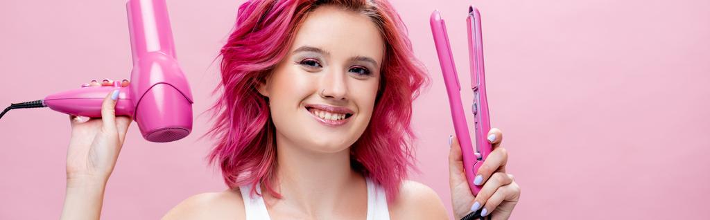 ピンクのパノラマショットで隔離された色鮮やかな髪を保持ストレートとヘアドライヤーを持つ若い女性 - 写真・画像