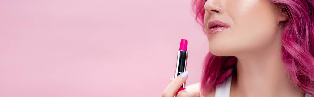 vista ritagliata di giovane donna che tiene il rossetto isolato su rosa, colpo panoramico - Foto, immagini