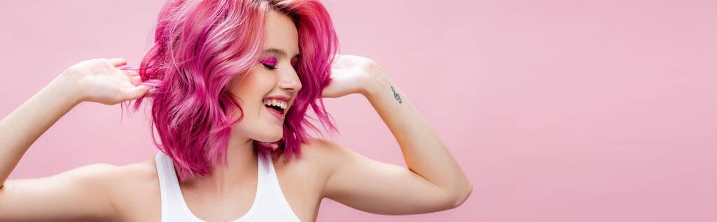 Nuori nainen koskettaa värikkäitä hiuksia eristetty vaaleanpunainen, panoraama laukaus - Valokuva, kuva