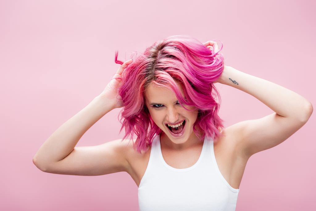 ενθουσιασμένοι νεαρή γυναίκα αγγίζοντας πολύχρωμα μαλλιά απομονώνονται σε ροζ - Φωτογραφία, εικόνα