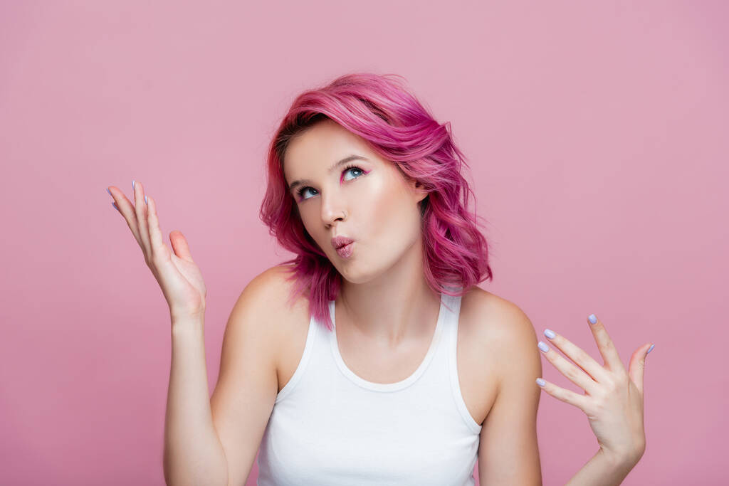 giovane donna con i capelli colorati labbra bronzanti e gesti isolati su rosa - Foto, immagini
