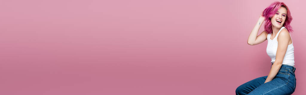 jovem com cabelo colorido e tatuagem sorrindo isolado em rosa, tiro panorâmico - Foto, Imagem