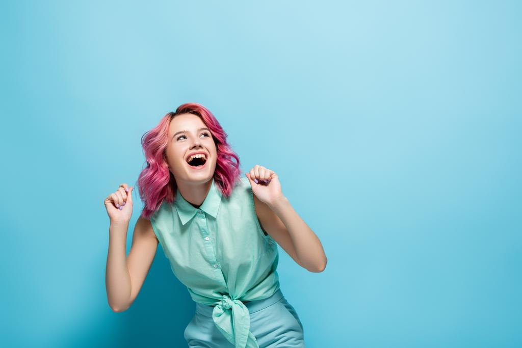 молодая женщина с розовыми волосами радуется на голубом фоне - Фото, изображение