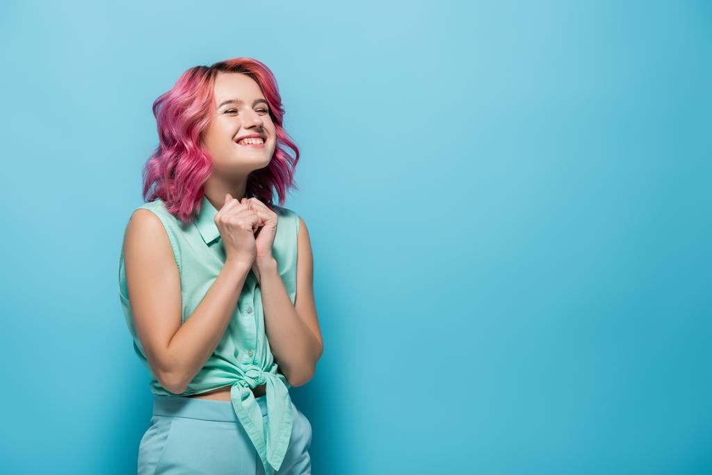mujer joven con el pelo rosa sonriendo sobre fondo azul - Foto, Imagen