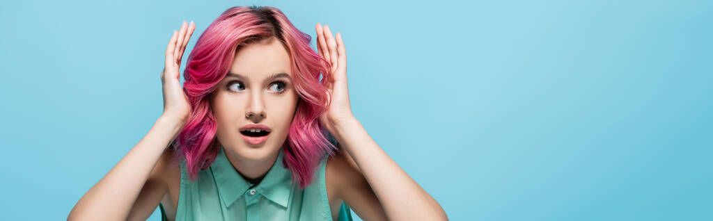 překvapená mladá žena s růžovými vlasy izolované na modrém pozadí, panoramatický záběr - Fotografie, Obrázek