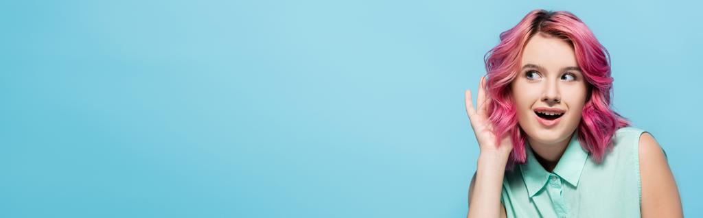 curiosa giovane donna dai capelli rosa che ascolta isolata sul blu, scatto panoramico - Foto, immagini