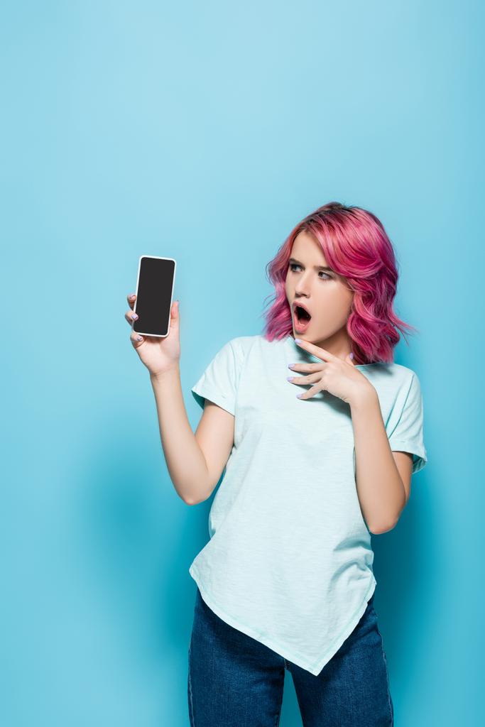 sokkos fiatal nő rózsaszín haj gazdaság okostelefon üres képernyő kék háttér - Fotó, kép