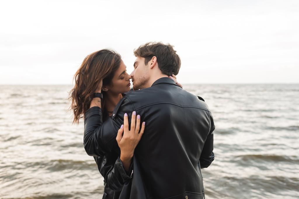 Uomo in pelle giacca baciare fidanzata con il mare sullo sfondo  - Foto, immagini