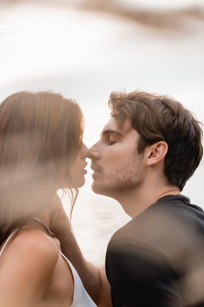 Focus selettivo dell'uomo baciare e toccare la ragazza vicino al mare  - Foto, immagini
