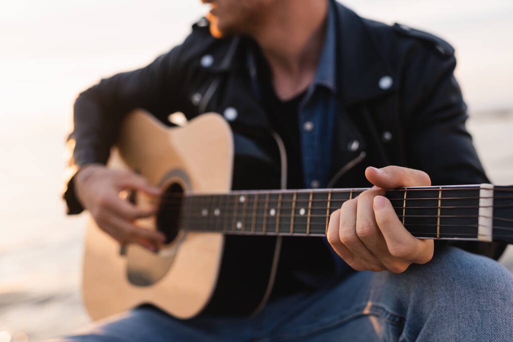 Vista recortada del joven tocando la guitarra acústica al aire libre  - Foto, Imagen