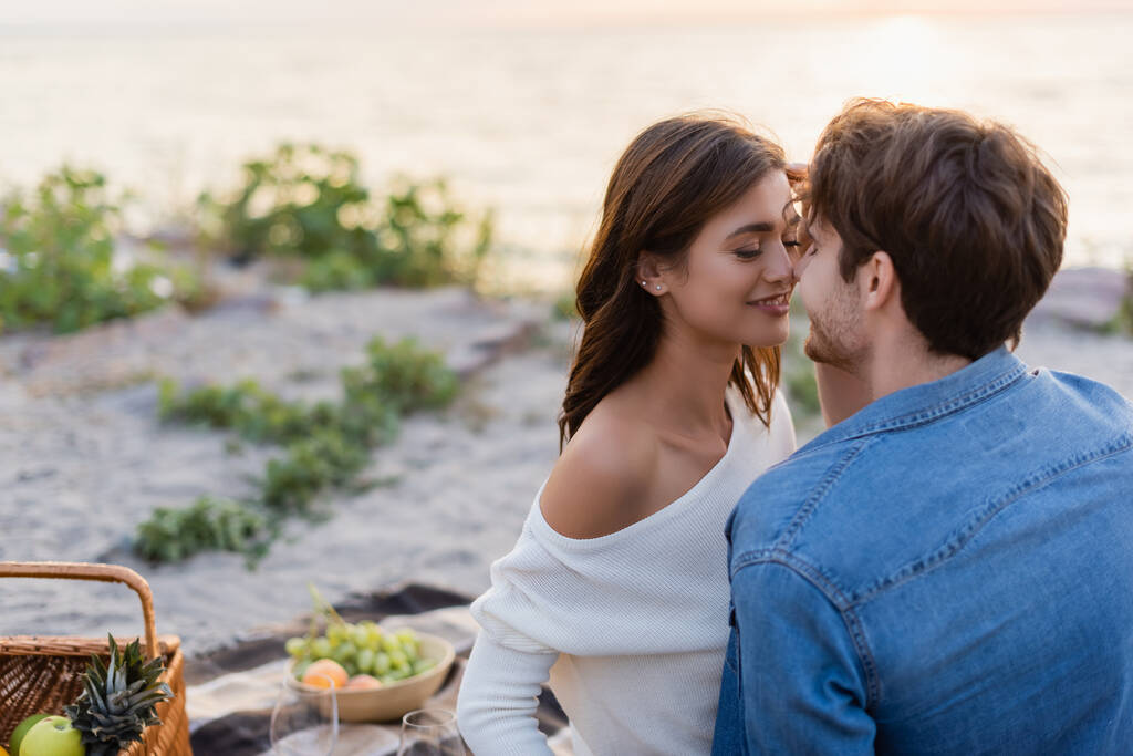 Hombre besando novia durante el picnic en la playa al atardecer  - Foto, imagen