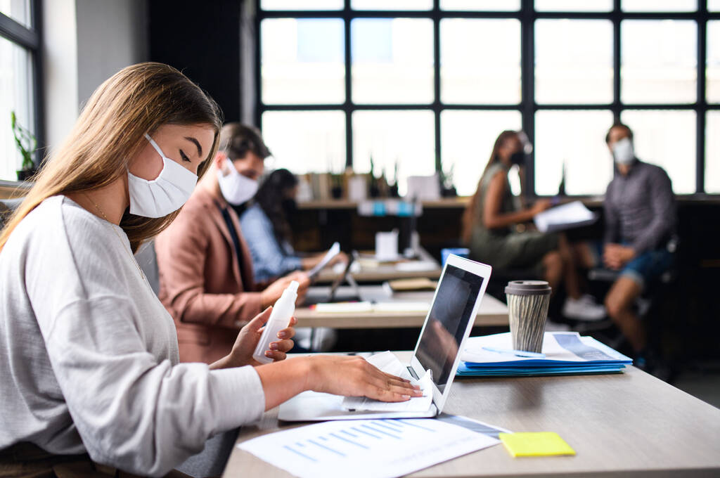 Les gens avec des masques pour le visage désinfectant à l'intérieur dans le bureau, retournent au travail après le verrouillage du coronavirus. - Photo, image