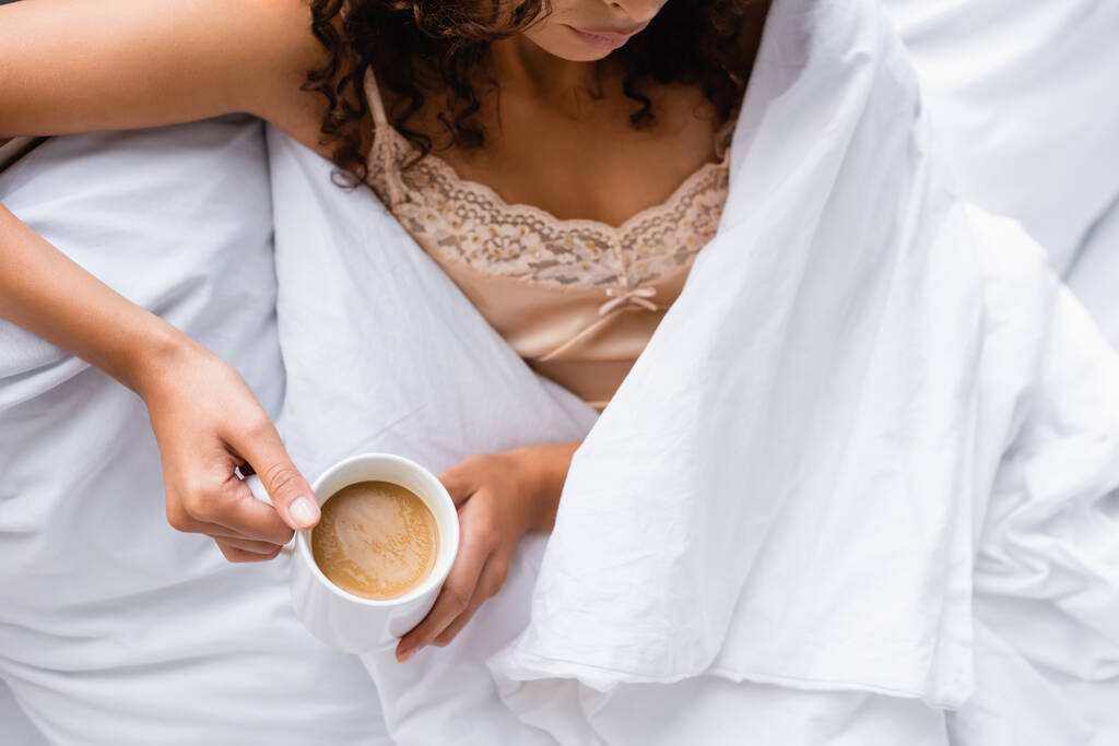 vue recadrée de la femme tenant tasse avec café au lit - Photo, image