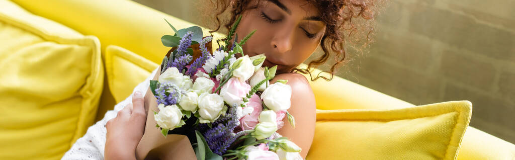 Panoramik tarlada elinde buket tutan ve çiçekleri koklayan genç bir kadın var. - Fotoğraf, Görsel