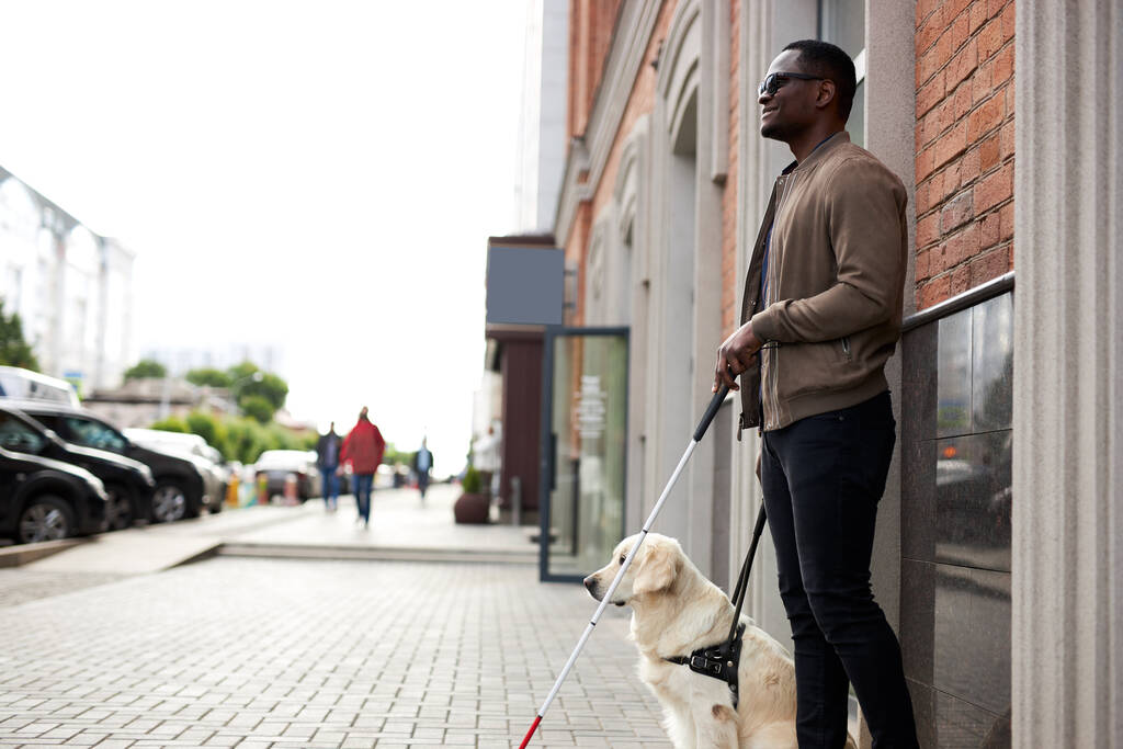 Afrikaans amerikaanse gehandicapte man met behulpzame hond - Foto, afbeelding