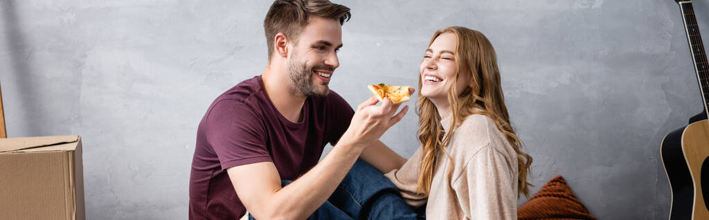 immagine orizzontale dell'uomo gioioso che tiene deliziosa pizza vicino alla ragazza - Foto, immagini
