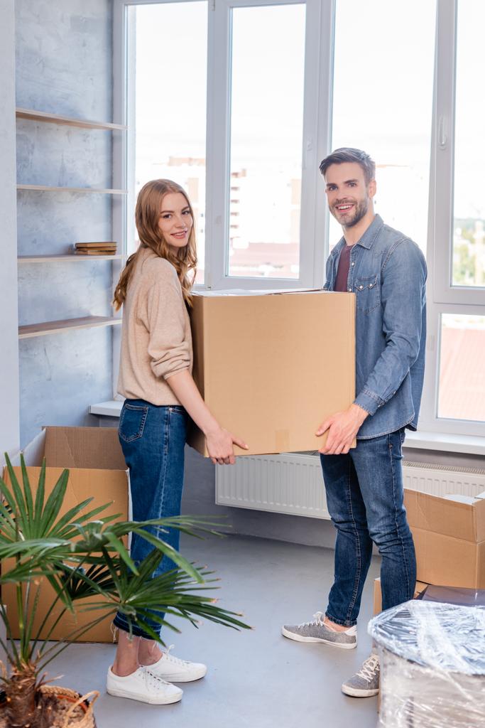 radostný muž a žena drží krabici a dívá se do kamery, pohybující se koncept - Fotografie, Obrázek