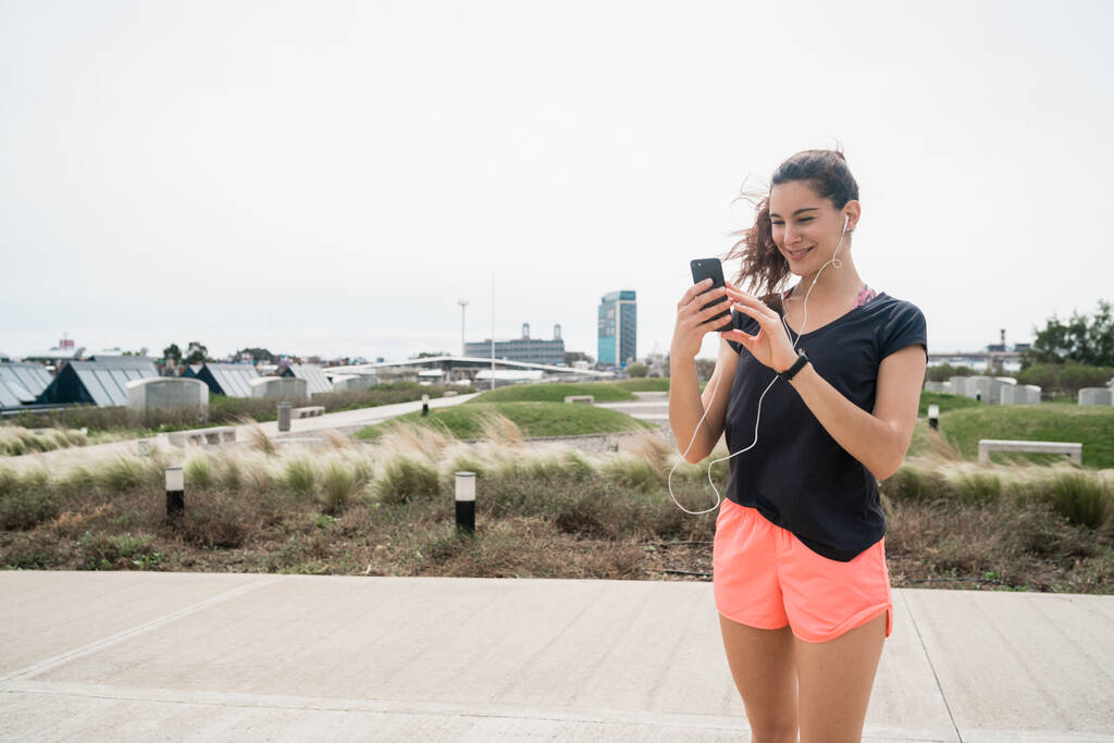 Портрет спортсменки, яка використовує свій мобільний телефон на перерві від тренувань. Спортивний і здоровий спосіб життя
. - Фото, зображення