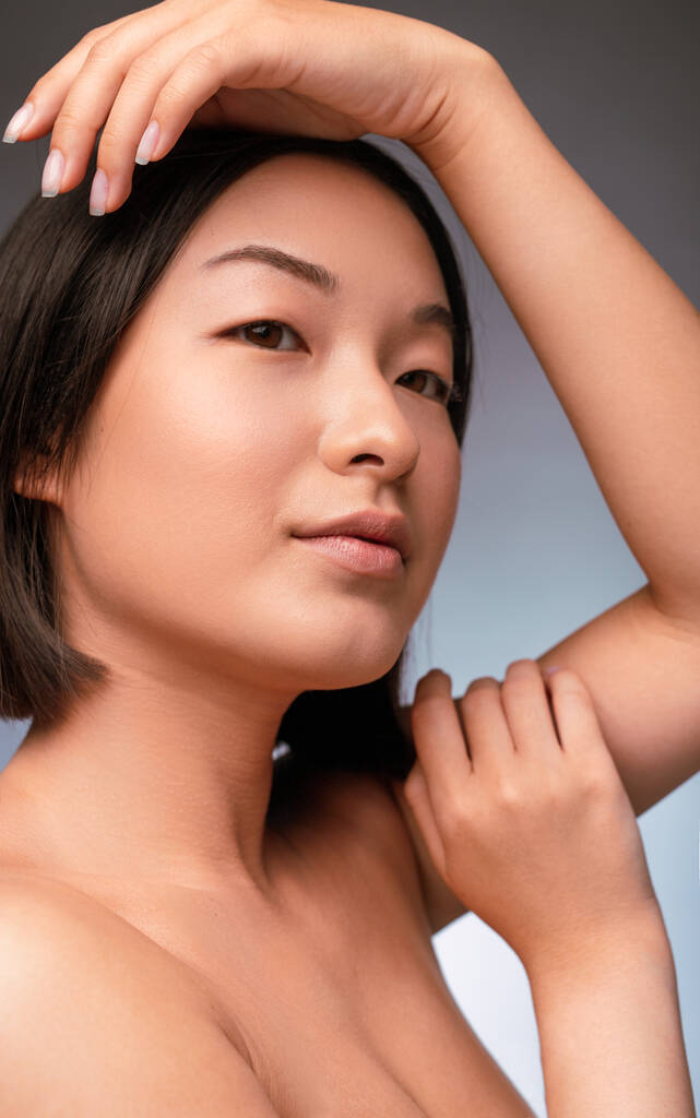 Bonita mujer asiática con el brazo levantado mirando hacia otro lado - Foto, imagen