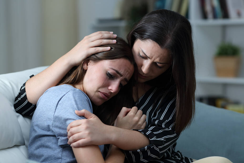 Smutný dospívající pláč je utěšen její sestra na gauči v obývacím pokoji doma  - Fotografie, Obrázek