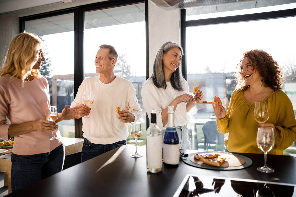 Ευτυχισμένοι ενήλικες γυναίκες και άνδρες απολαμβάνοντας το κρασί στο σπίτι - Φωτογραφία, εικόνα