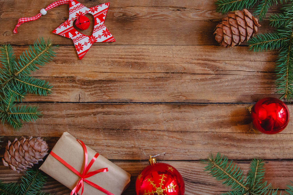 Karácsonyi lakás feküdt fenyő ágak, kézműves ajándék, kúp, piros baubles és csillag alakú játék egy fa háttér. Másolótér.  - Fotó, kép