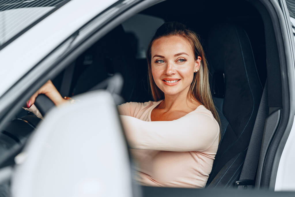 Młoda atrakcyjna biała kobieta siedzi w nowo zakupionym samochodzie - Zdjęcie, obraz