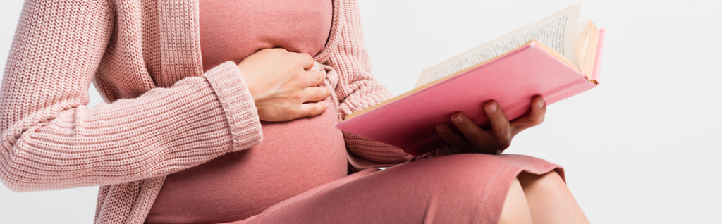 panoramatické plodiny těhotné ženy drží knihu a dotýká břicho izolované na bílém - Fotografie, Obrázek