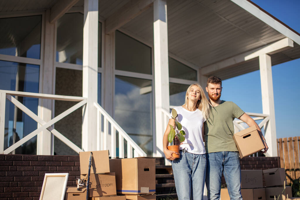Mann und Frau stehen mit Kisten vor neuem Eigenheim - Foto, Bild