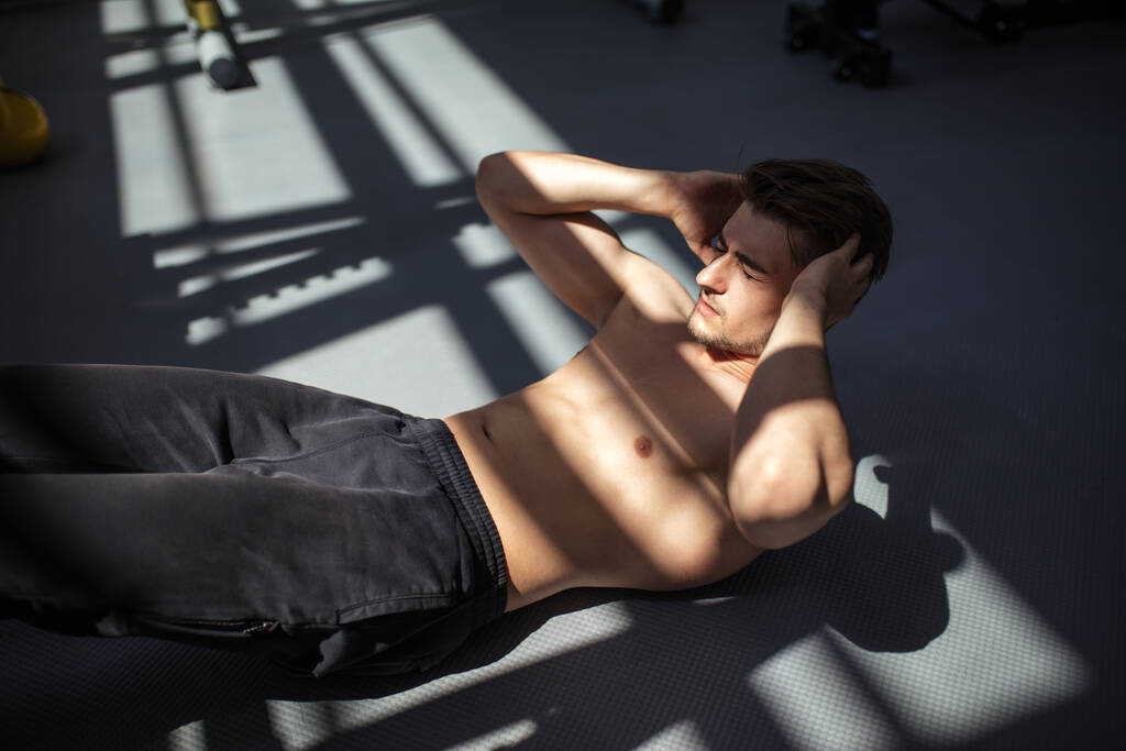 Hombre en ejercicios musculares abdominales crujientes durante el entrenamiento en gimnasio de fitness. - Foto, imagen