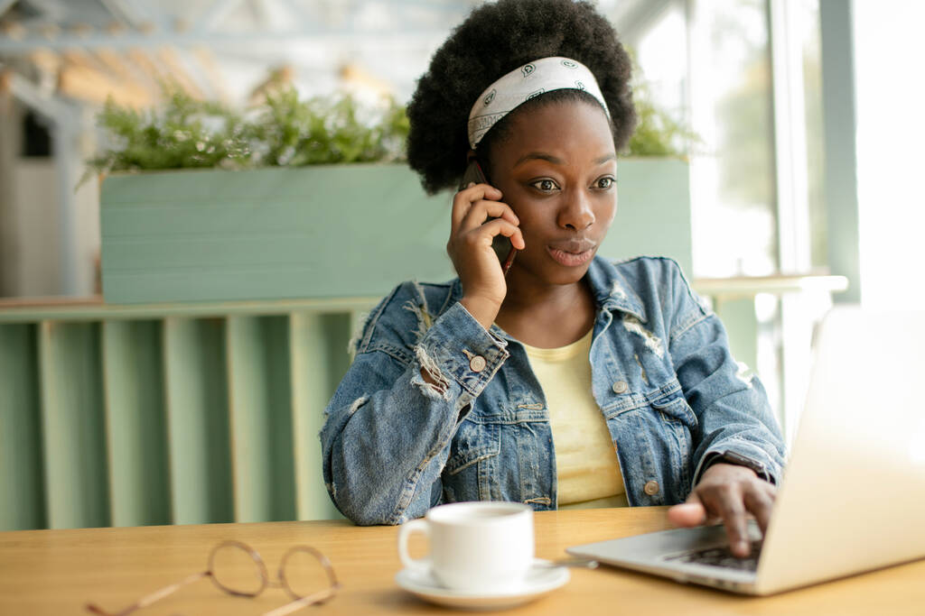 Jovem mulher africana com cabelos escuros crespos compras on-line enquanto sentado no café. - Foto, Imagem