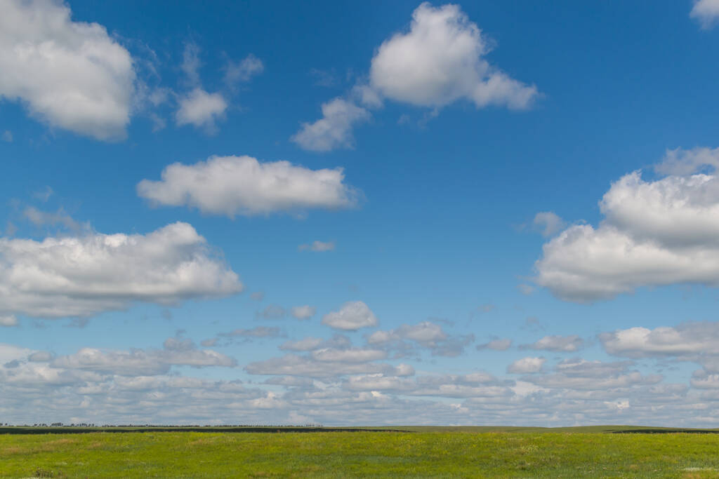 witte pluizige heldere wolken in blauwe lucht met groen veld, open ruimte - Foto, afbeelding