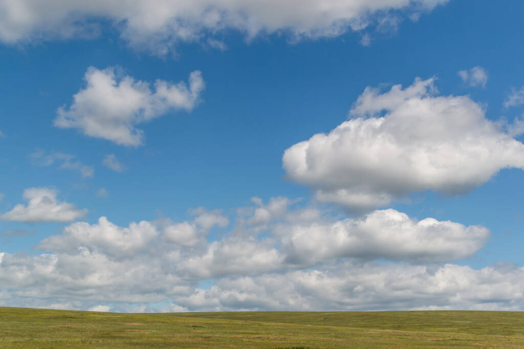 bílé nadýchané mraky na jasně modré obloze se zeleným polem, otevřený prostor - Fotografie, Obrázek