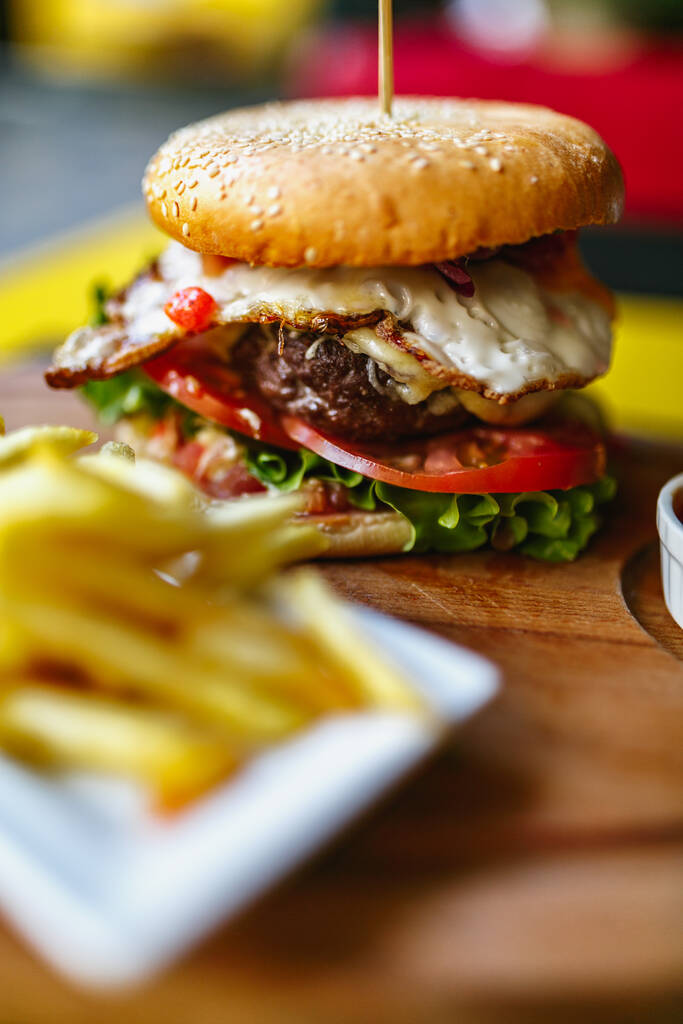 Вертикальный снимок свежего вкусного бургера и картошки фри на деревянном столе - Фото, изображение