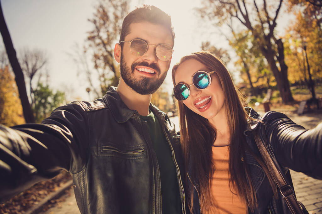 Pozitif neşeli bir çiftin portresi, Eylül ayı şehir merkezindeki parkta selfie çekiyor. Deri ceket giyiyor. - Fotoğraf, Görsel