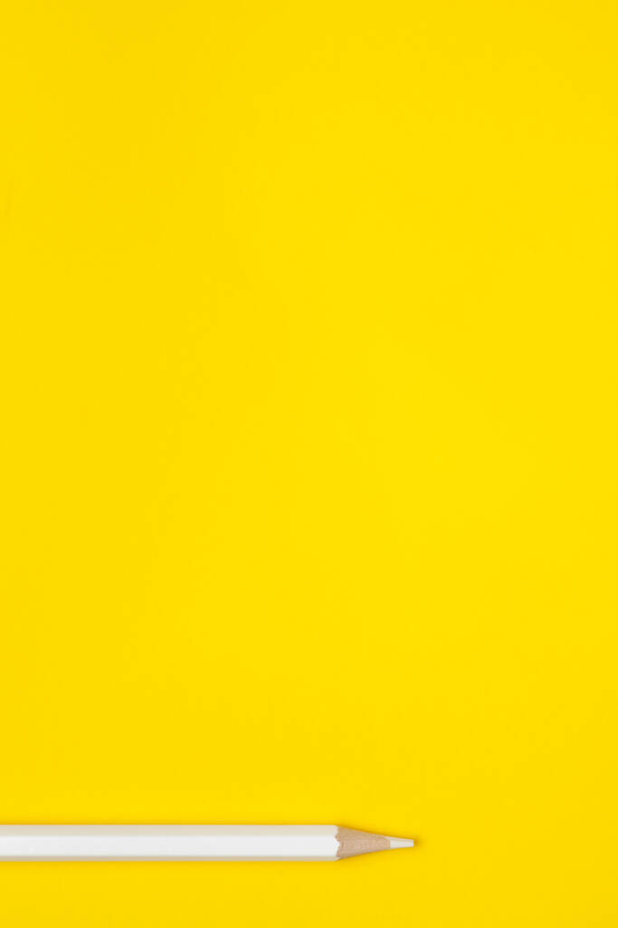 Вертикальный белый острый деревянный карандаш на ярко-желтом фоне, изолированный, пространство для копирования, приглушенный - Фото, изображение