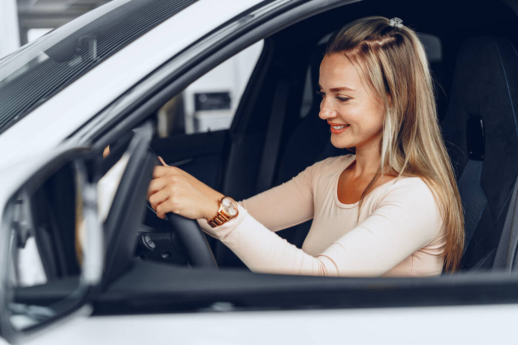 Młoda atrakcyjna biała kobieta siedzi w nowo zakupionym samochodzie - Zdjęcie, obraz