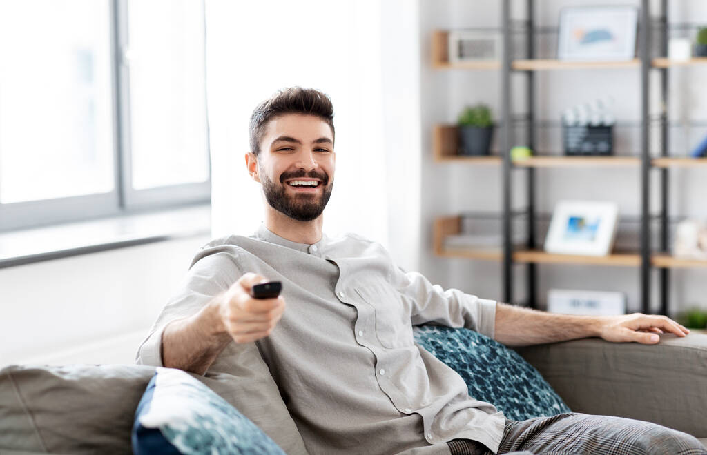 onnellinen mies kaukosäätimellä katsomassa televisiota kotona - Valokuva, kuva