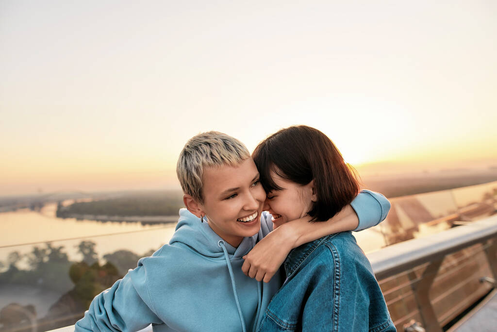 Joven pareja lesbiana abrazándose mientras se divierten juntos al aire libre, Dos chicas disfrutando de momentos románticos al amanecer - Foto, imagen