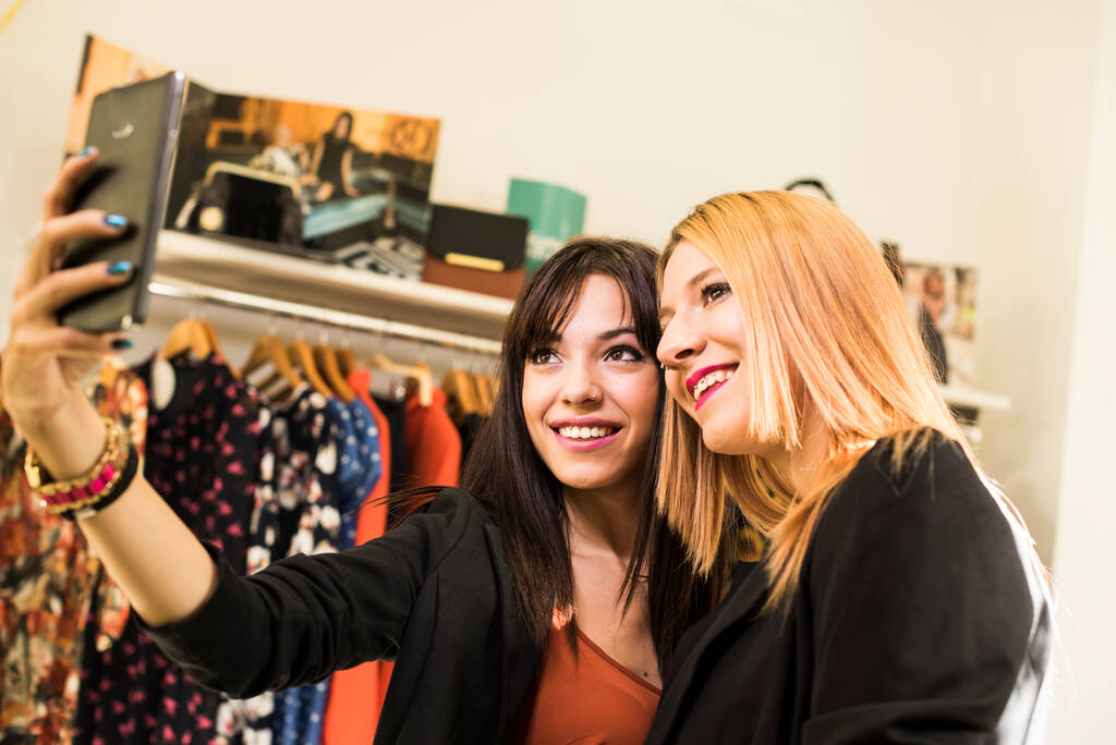Deux jolies femmes faisant du shopping dans un magasin de mode, prenant selfie - Photo, image