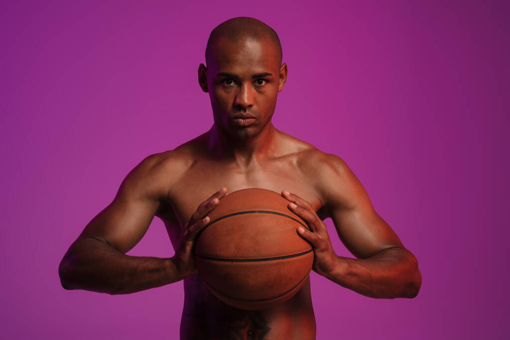 Image of a handsome concentrated strong african fitness sports man posing isolated over pink wall background while holding basketball - Photo, Image