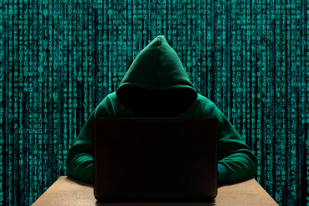 Haker w kapturze przy komputerze. Cyberszpiegostwo i bezpieczeństwo cyfrowe - Zdjęcie, obraz