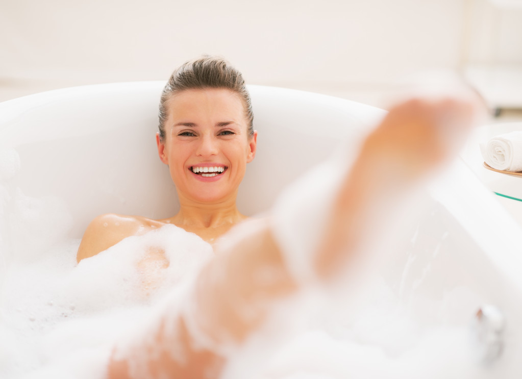 Усміхнена молода жінка весело проводить час у ванній
 - Фото, зображення